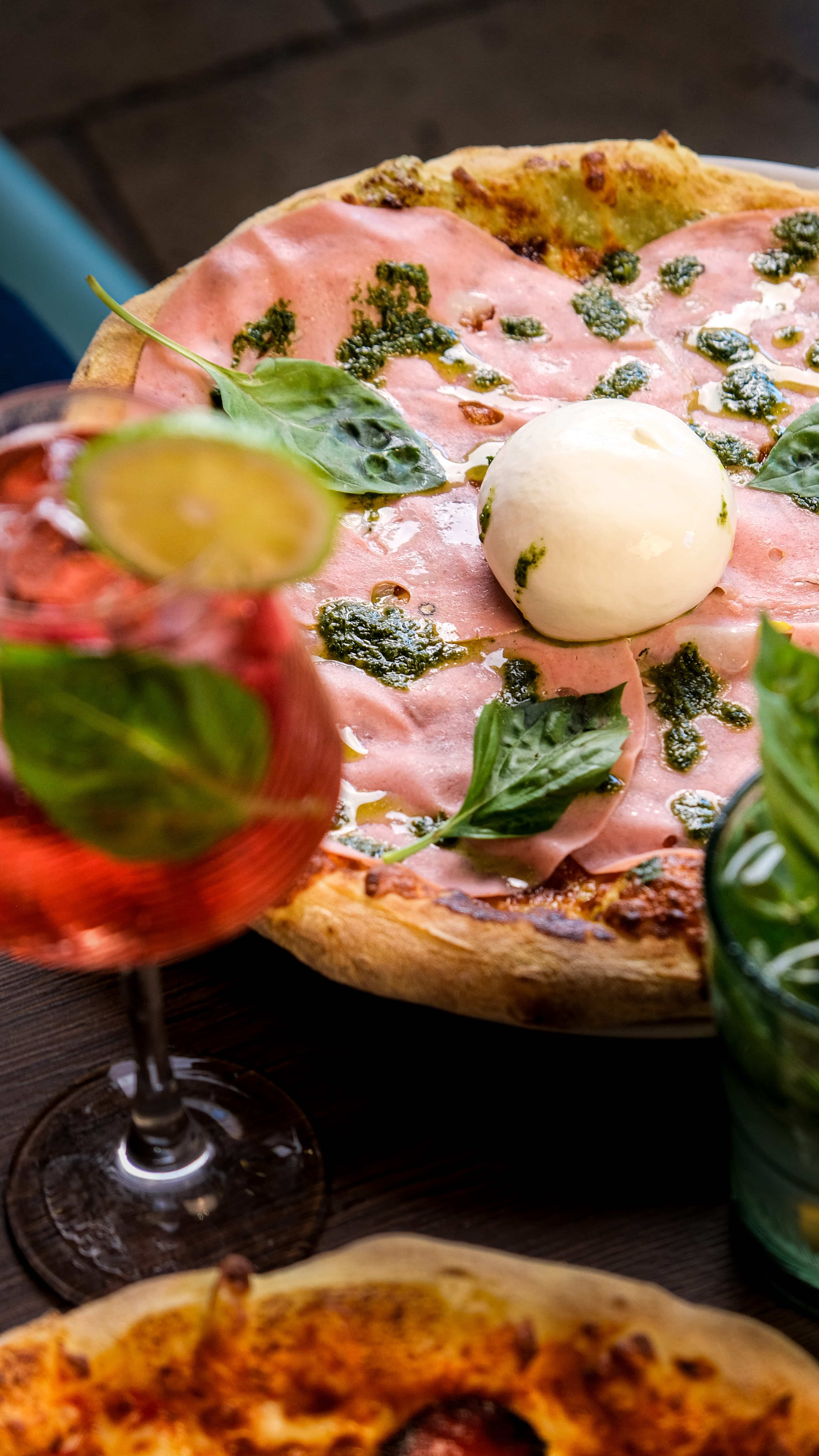 Pizza Fabioli à la mortadelle, burrata et pesto, servie avec un spritz