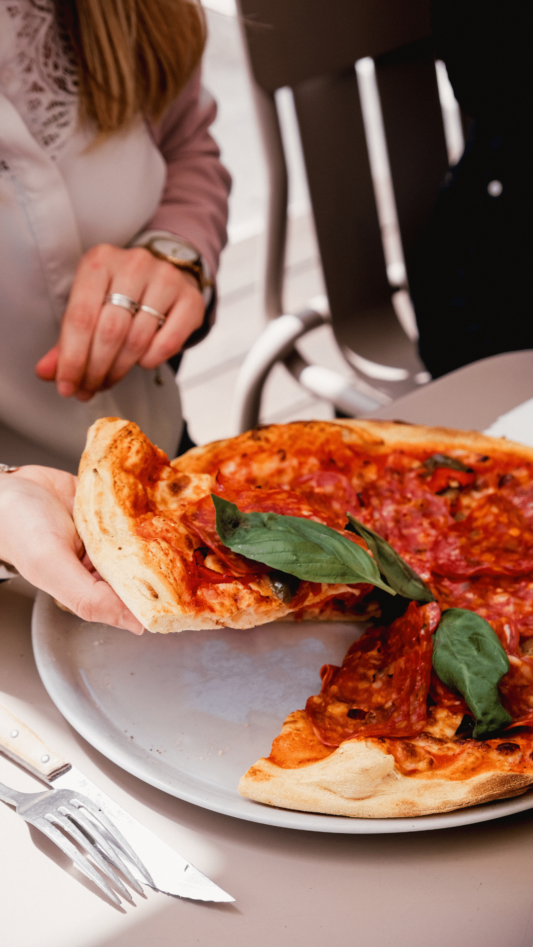 Cliente prenant une part de pizza au salami et basilic en terrasse